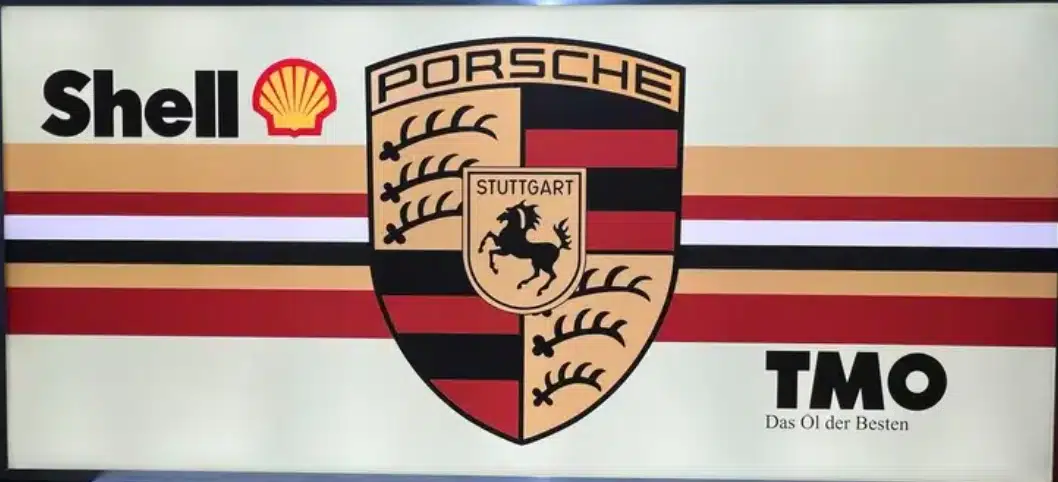Изображение демонстрирует партнерство знаменитых брендов Shell и Porsche представленное их эмблемами и текстом TMO на ярком полосатом фоне.