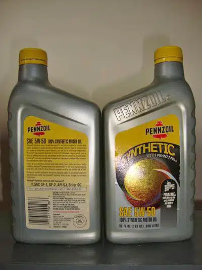 На изображении две серебристые бутылки моторного масла Pennzoil SAE 5W-50, синтетика с желтыми этикетками.