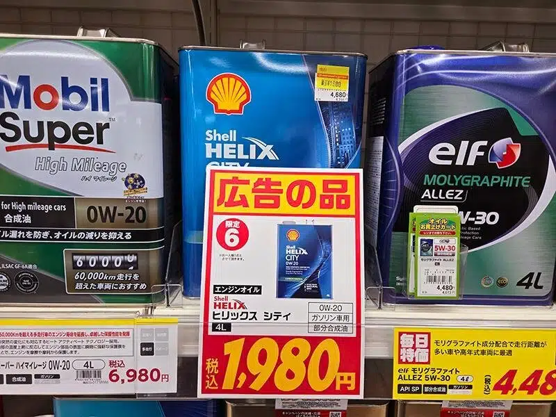 На полке в магазине представлены моторные масла известных брендов Mobil Shell и Elf с ценниками в японских йенах.