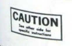 На белом фоне табличка с надписью Caution и текстом про инструкции на обороте.