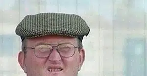 Мужчина в кепке и очках смотрит в камеру, слегка улыбаясь.