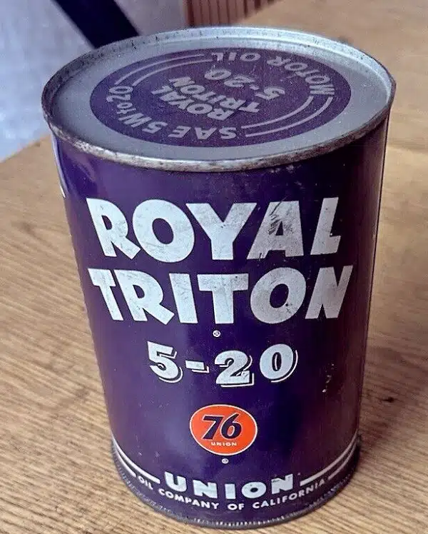 Пурпурная металлическая банка ROYAL TRITON 5 20 от компании UNION OIL с классическим логотипом 76 представлена на деревянном фоне детализировано.