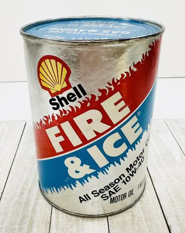 На снимке винтажная жестяная банка моторного масла Shell с контрастным дизайном огонь и лед предмет коллекционирования отражающий дух классических автомобилей.