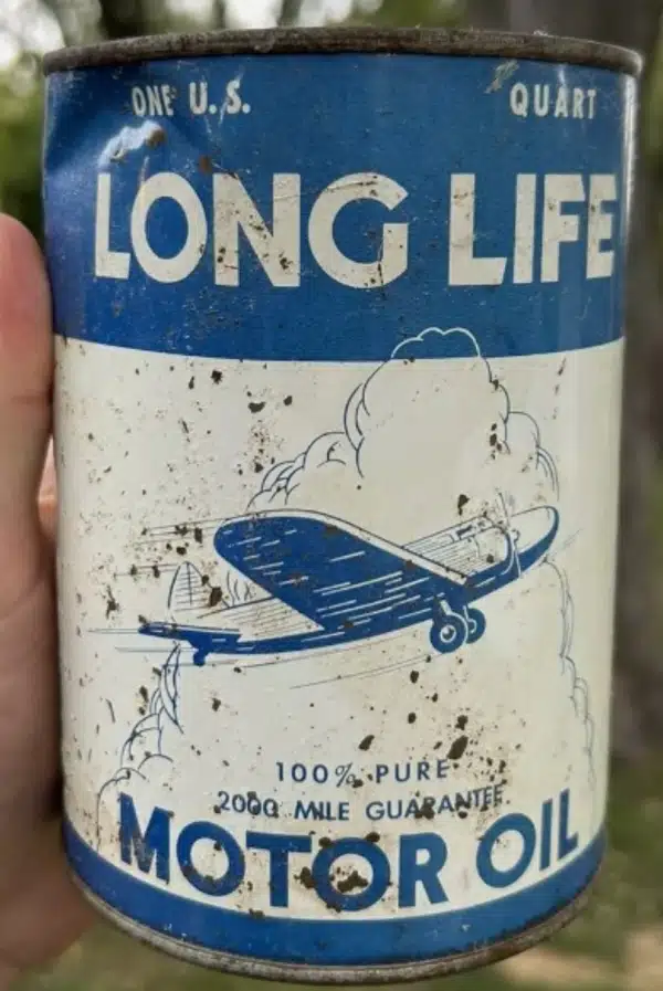 Ретро банка моторного масла Long Life с рисунком самолёта на белом фоне.