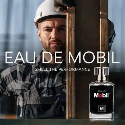 Мужчина в каске и комбинезоне и флакон парфюма Eau de Mobil на рекламном постере.