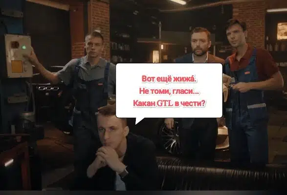 Четверо мужчин в автосервисе обсуждают какой GTL в чести с автомобилем на заднем плане.