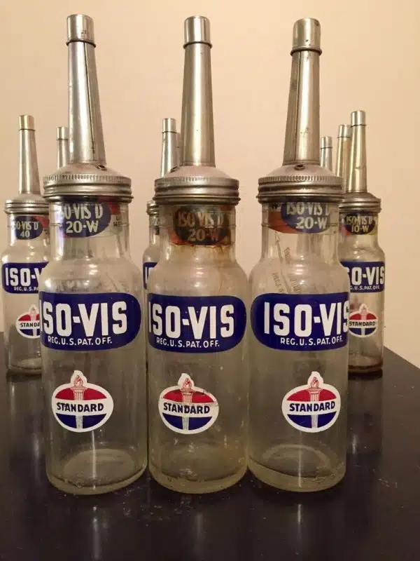 Набор старых стеклянных масленок Iso-Vis Standard Oil с металлическими носиками и фирменными этикетками на переднем плане.