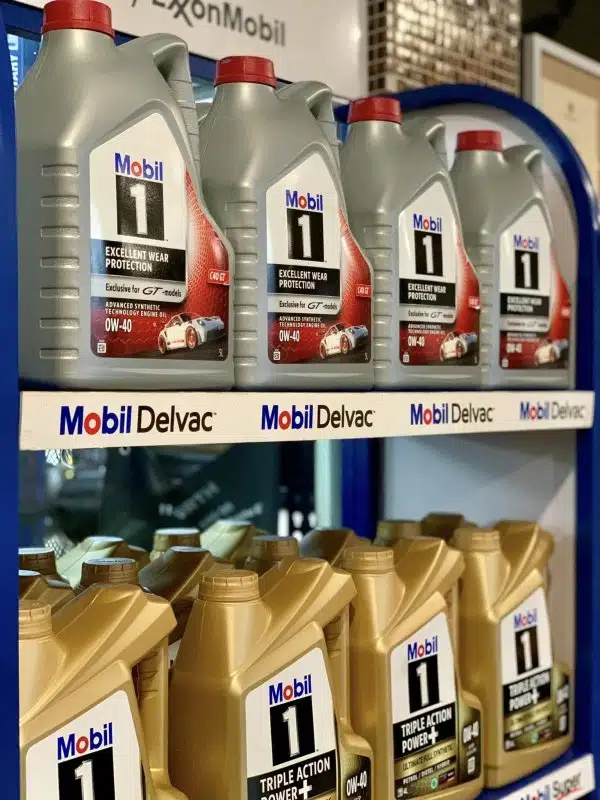Множество серых и золотых резервуаров с логотипом Mobil 1 аккуратно выстроены демонстрируя выбор передовых смазочных материалов для современной техники.