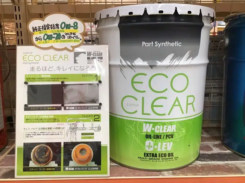 На полке банка и рекламный стенд моторного масла Eco Clear с информацией о чистке двигателя.