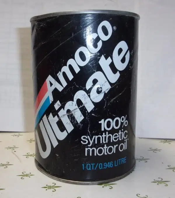 На фото банка моторного масла Amoco Ultimate в черной упаковке с белыми надписями и цветными полосками.