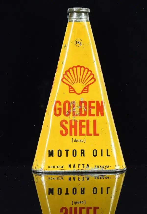 На жёлтом фоне старая треугольная банка моторного масла Golden Shell с красным логотипом ракушки и надписями.