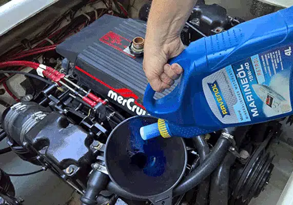 Рука заботливо направляет поток синего морского масла Ravenol в двигатель Mercruiser с помощью воронки обеспечивая долгую жизнь мотора.