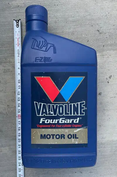 Синяя канистра моторного масла Valvoline FourGard рядом с измерительной лентой.
