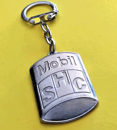 Металлический брелок с надписью Mobil SHC на желтом фоне.