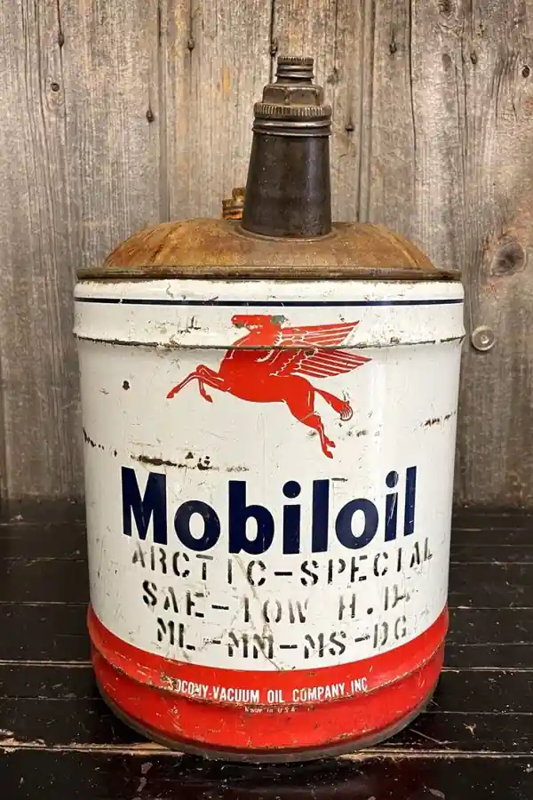 Винтажная металлическая канистра Mobiloil с красным крылатым конем на фоне деревянной стены выглядит как раритет.