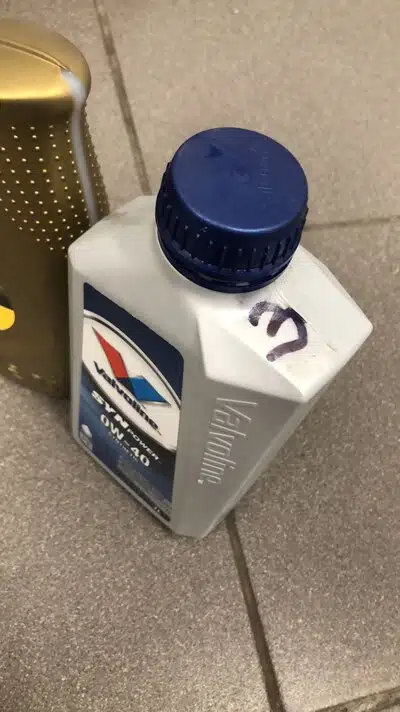 На фото белая канистра моторного масла Valvoline SynPower 0W-40 с синей крышкой и пометкой чернилами.
