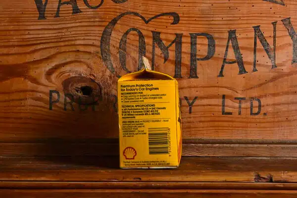 Желтая упаковка моторного масла Shell на фоне деревянной доски с надписью Company.