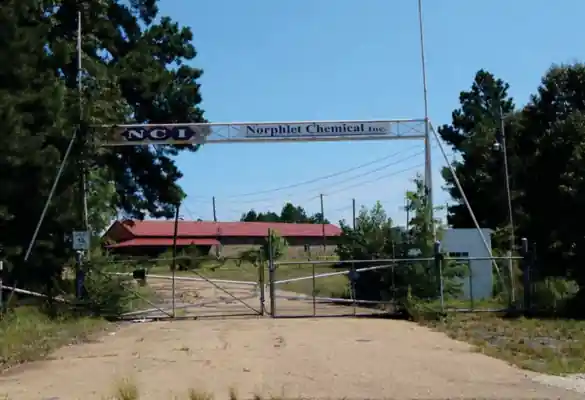 Табличка Norphlet Chemical Inc над воротами входа на территорию завода.