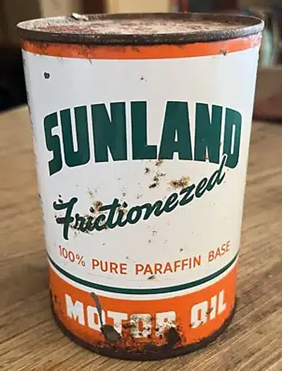 Винтажная банка моторного масла Sunland с потертостями и ржавчиной, с надписями и оранжевыми полосами.
