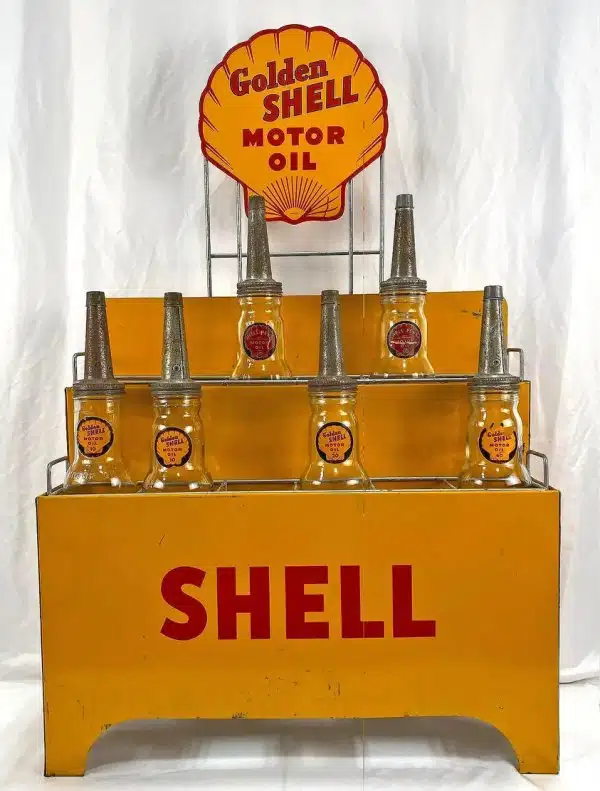 Рекламная стойка Shell с бутылками масла Golden Shell Motor Oil на желтом фоне.