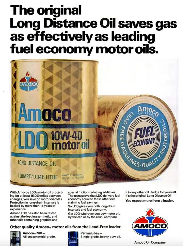 Золотистые банки моторного масла Amoco LDO 10W 40 на винтажной рекламе символизируют экономию и большой пробег двигателя автомобиля.